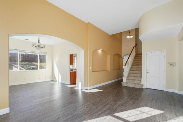 unfurnished living room featuring dark hardwood / wood-style floors and an inviting chandelier