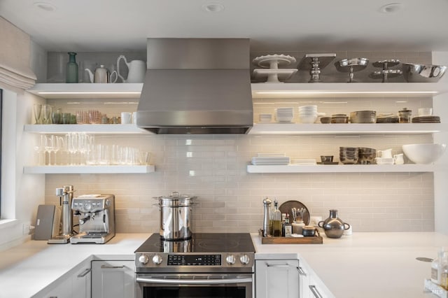 kitchen with backsplash, electric range, white cabinets, and island exhaust hood