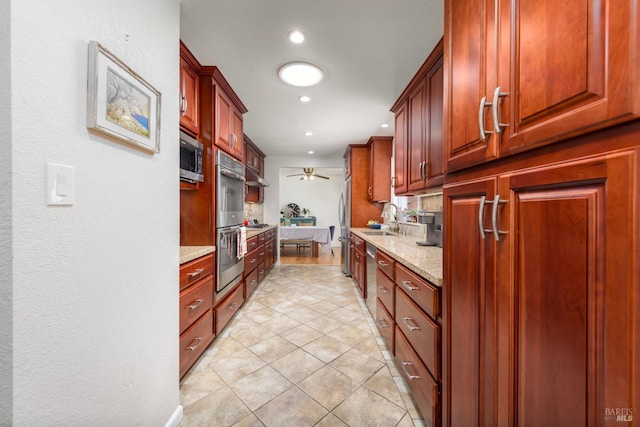 kitchen featuring ceiling fan, sink, light tile patterned flooring, appliances with stainless steel finishes, and light stone counters