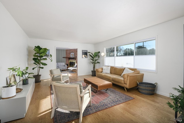 living room with a brick fireplace and light wood-type flooring