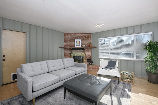 living room with a brick fireplace and light wood-type flooring