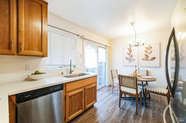 kitchen with pendant lighting, dark wood-type flooring, stainless steel appliances, sink, and a chandelier