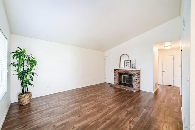 unfurnished living room with dark wood-type flooring, lofted ceiling, and a brick fireplace