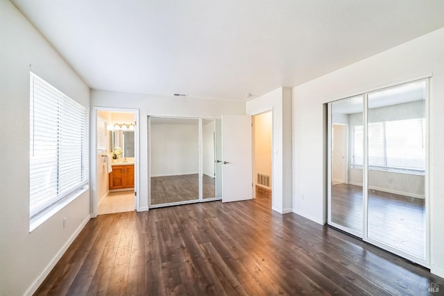 unfurnished bedroom featuring dark hardwood / wood-style flooring and connected bathroom