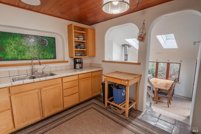 kitchen featuring a skylight, wood ceiling, tile counters, and sink