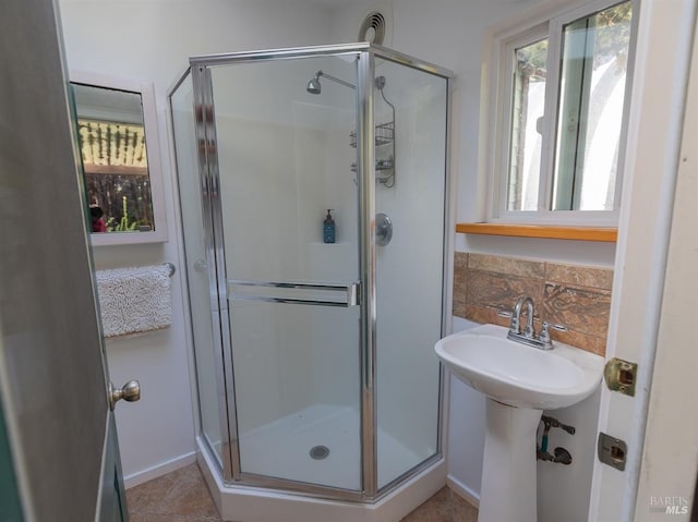 bathroom with tile patterned floors, backsplash, and a shower with door