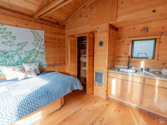 bedroom with vaulted ceiling with beams, light wood-type flooring, sink, and wooden walls