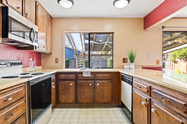 kitchen with appliances with stainless steel finishes, light countertops, and a sink