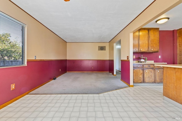 kitchen featuring baseboards, light countertops, visible vents, and brown cabinets