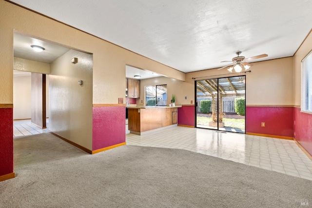 unfurnished room featuring light carpet, a textured wall, and ceiling fan