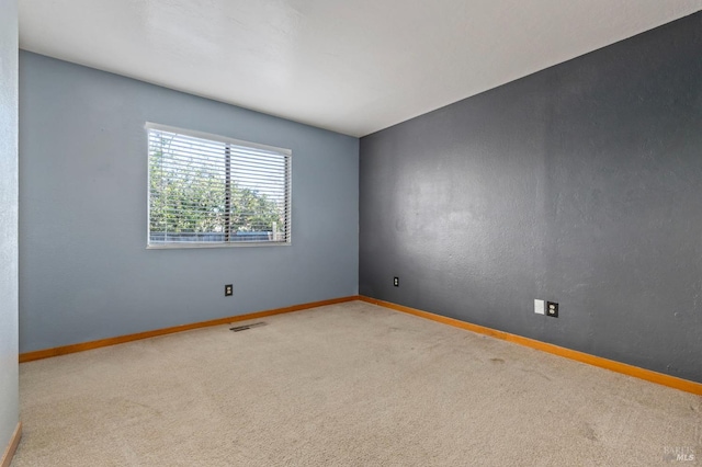 carpeted spare room with visible vents and baseboards