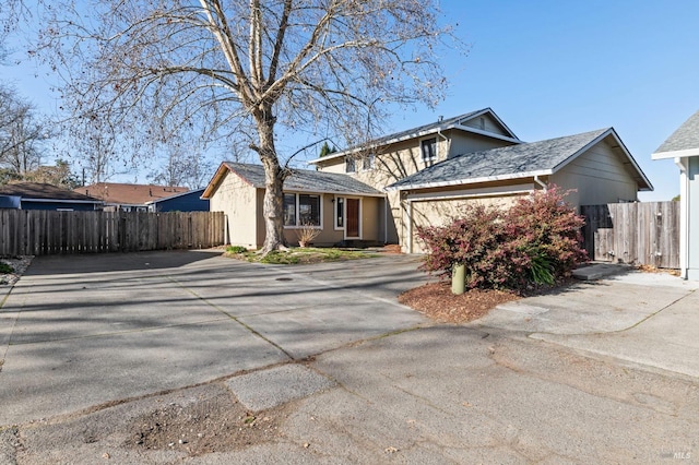 view of front of home featuring a garage, concrete driveway, fence, and stucco siding