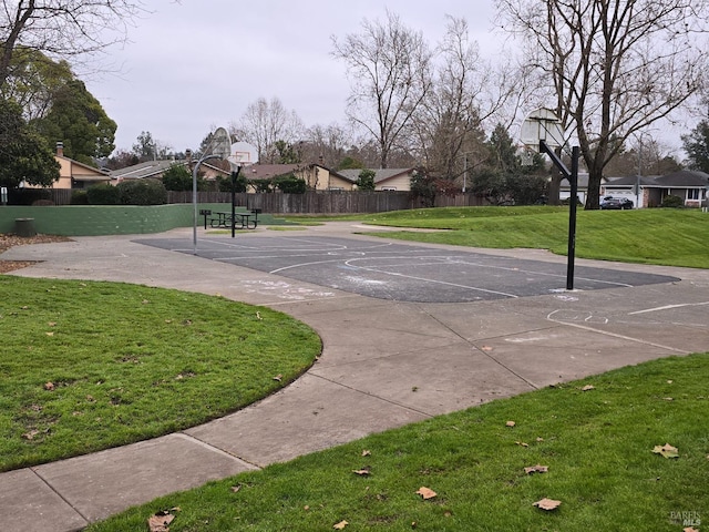 view of sport court featuring community basketball court, fence, a lawn, and a residential view