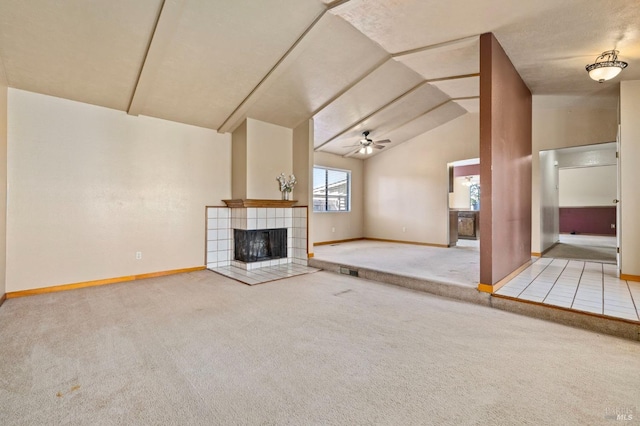 unfurnished living room featuring ceiling fan, light carpet, a fireplace, baseboards, and vaulted ceiling