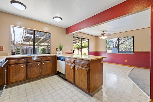 kitchen featuring a peninsula, light countertops, stainless steel dishwasher, light floors, and beamed ceiling