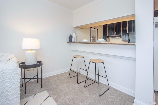 kitchen featuring crown molding, a breakfast bar area, light colored carpet, and kitchen peninsula