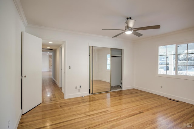 unfurnished bedroom with ceiling fan, crown molding, light hardwood / wood-style floors, and a closet