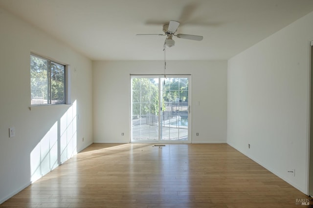 empty room with ceiling fan, plenty of natural light, and light hardwood / wood-style floors