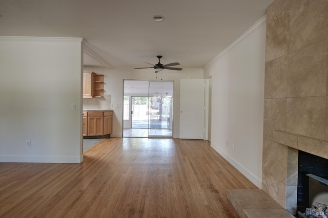 unfurnished living room featuring ceiling fan, light hardwood / wood-style floors, crown molding, and a fireplace