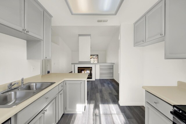 kitchen featuring gray cabinets, kitchen peninsula, sink, dark wood-type flooring, and range with electric cooktop