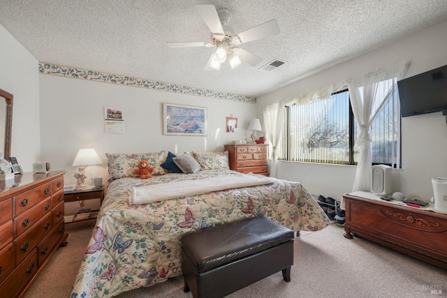 carpeted bedroom featuring ceiling fan and a textured ceiling