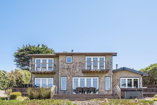 back of property with a hot tub and a balcony