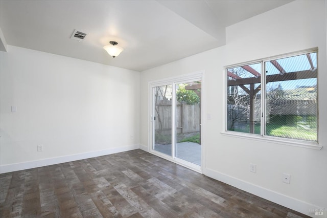 spare room with visible vents, baseboards, and dark wood-style floors