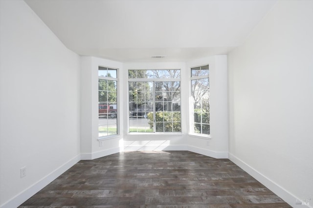spare room featuring visible vents, baseboards, and wood finished floors