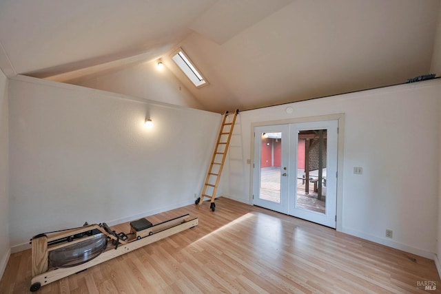 empty room featuring french doors, plenty of natural light, vaulted ceiling with skylight, and hardwood / wood-style flooring