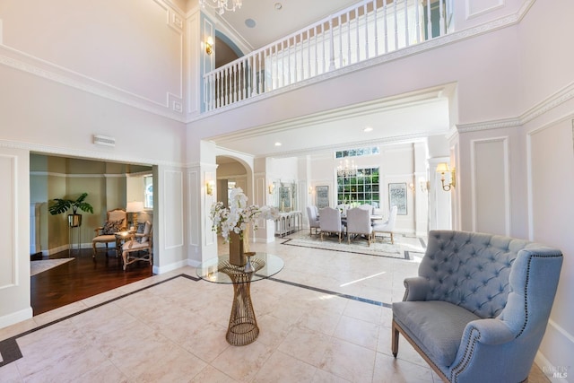 foyer entrance featuring ornamental molding, tile patterned flooring, decorative columns, and a decorative wall