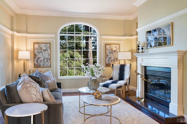 living area featuring ornamental molding, wood finished floors, a glass covered fireplace, and baseboards