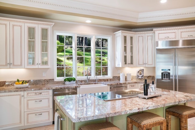 kitchen featuring light stone counters, a center island, appliances with stainless steel finishes, a sink, and a kitchen breakfast bar