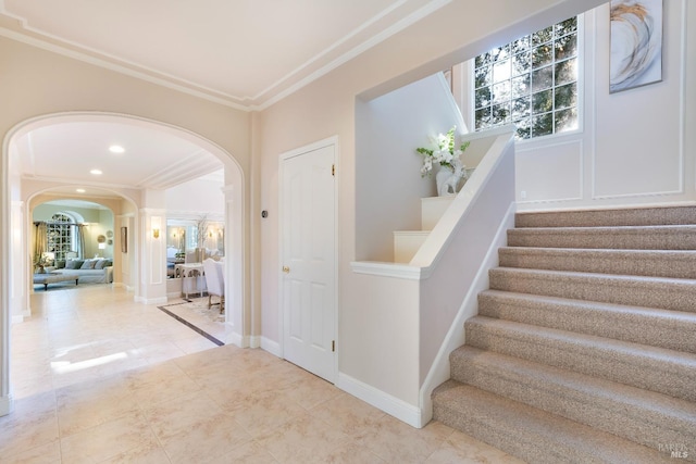 staircase with arched walkways, recessed lighting, baseboards, tile patterned floors, and crown molding