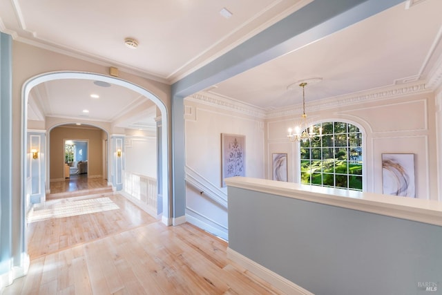 corridor with baseboards, arched walkways, wood finished floors, crown molding, and a chandelier