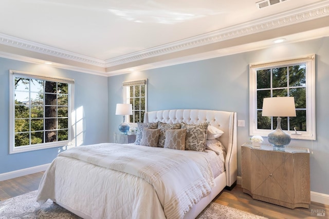 bedroom featuring ornamental molding, visible vents, baseboards, and wood finished floors