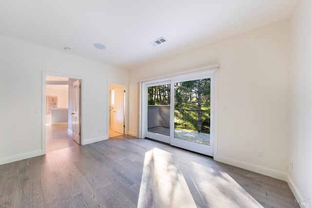 spare room featuring wood finished floors, visible vents, and baseboards