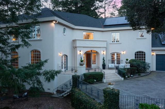 view of front of home featuring covered porch, a shingled roof, roof mounted solar panels, and french doors