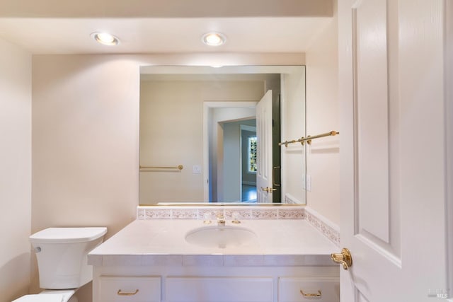 half bath featuring recessed lighting, vanity, and toilet