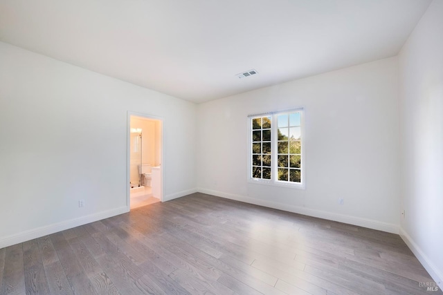 empty room featuring baseboards, visible vents, and wood finished floors