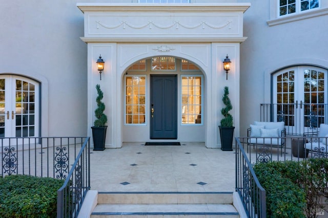 entrance to property with french doors, a patio, and stucco siding