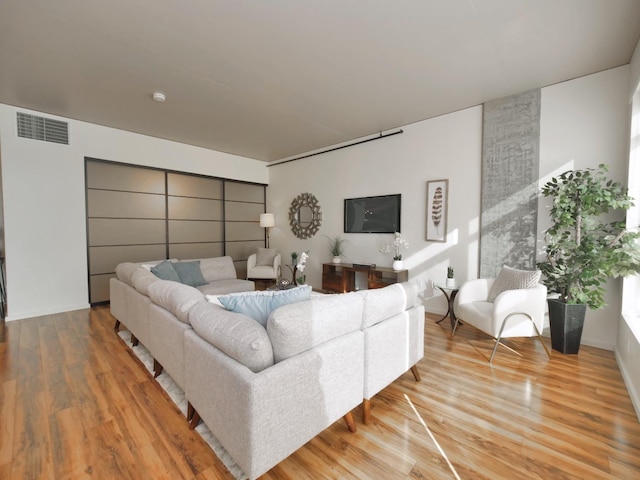 living room featuring visible vents, baseboards, and wood finished floors