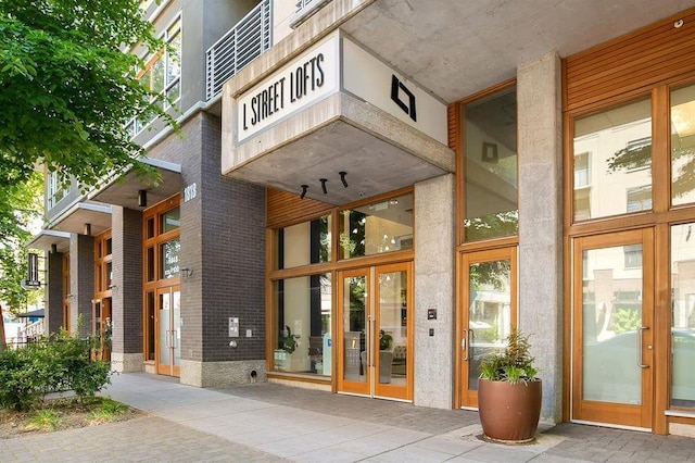 view of exterior entry featuring french doors and brick siding