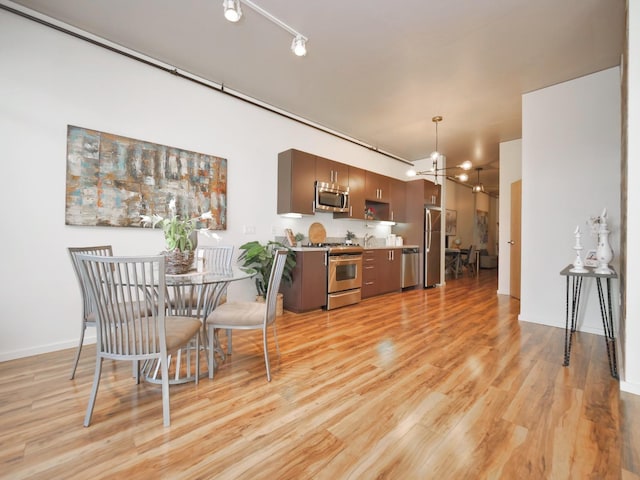 dining room with a chandelier, rail lighting, and light wood finished floors