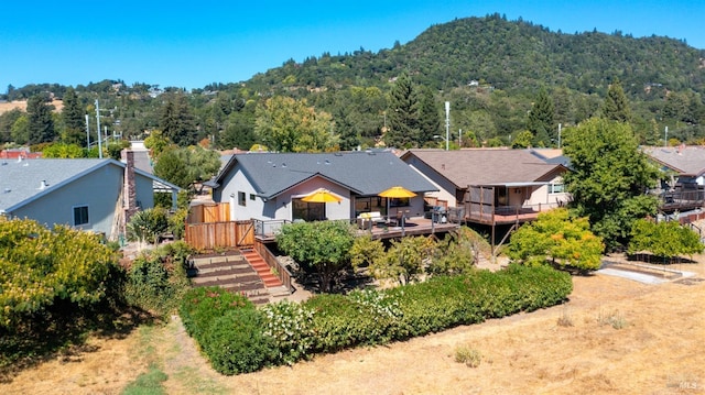 view of front of property with stairs, a view of trees, and a wooden deck