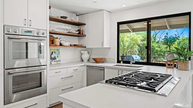 kitchen featuring open shelves, white cabinets, stainless steel appliances, and a sink