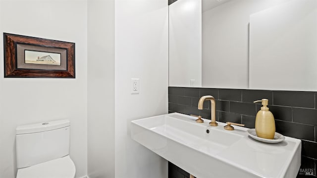 half bath featuring tasteful backsplash and toilet