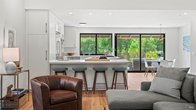 kitchen featuring a breakfast bar, open floor plan, a peninsula, light countertops, and white cabinetry