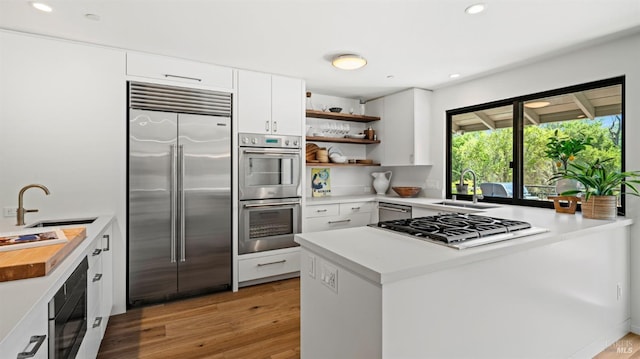 kitchen featuring a sink, stainless steel appliances, a peninsula, and open shelves