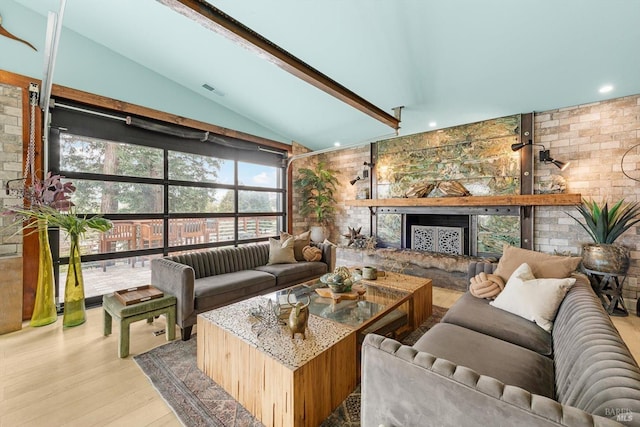 living area featuring a fireplace with raised hearth, vaulted ceiling, and wood finished floors