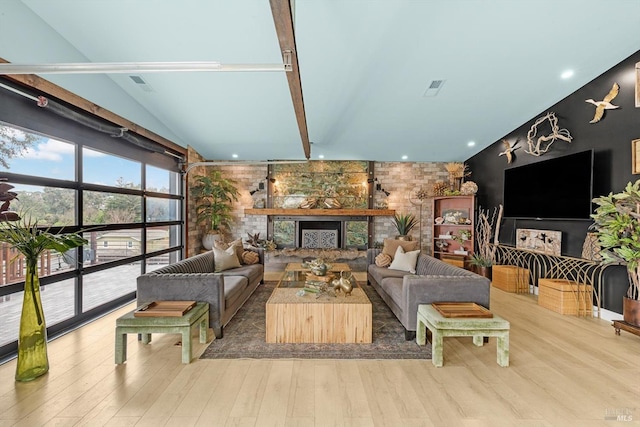 living room featuring a fireplace, visible vents, vaulted ceiling, and wood finished floors